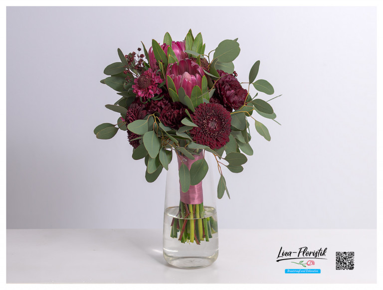 Brautstrauß mit roten Proteas, roter Scabiosa, roten Nelken, roten Gerbera, Eukalyptus und rot gefärbtem Schleierkraut