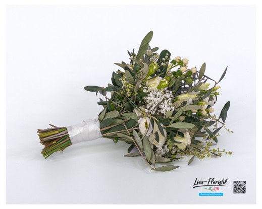Seitlich liegender Brautstrauß in Cremefarben mit Polyantharosen, weißem Lisianthus, Schleierkraut, weißem Hypericum und Olivenzweigen – locker gebunden und mit weißem Satinband umwickelt für einen natürlichen, eleganten Look.
